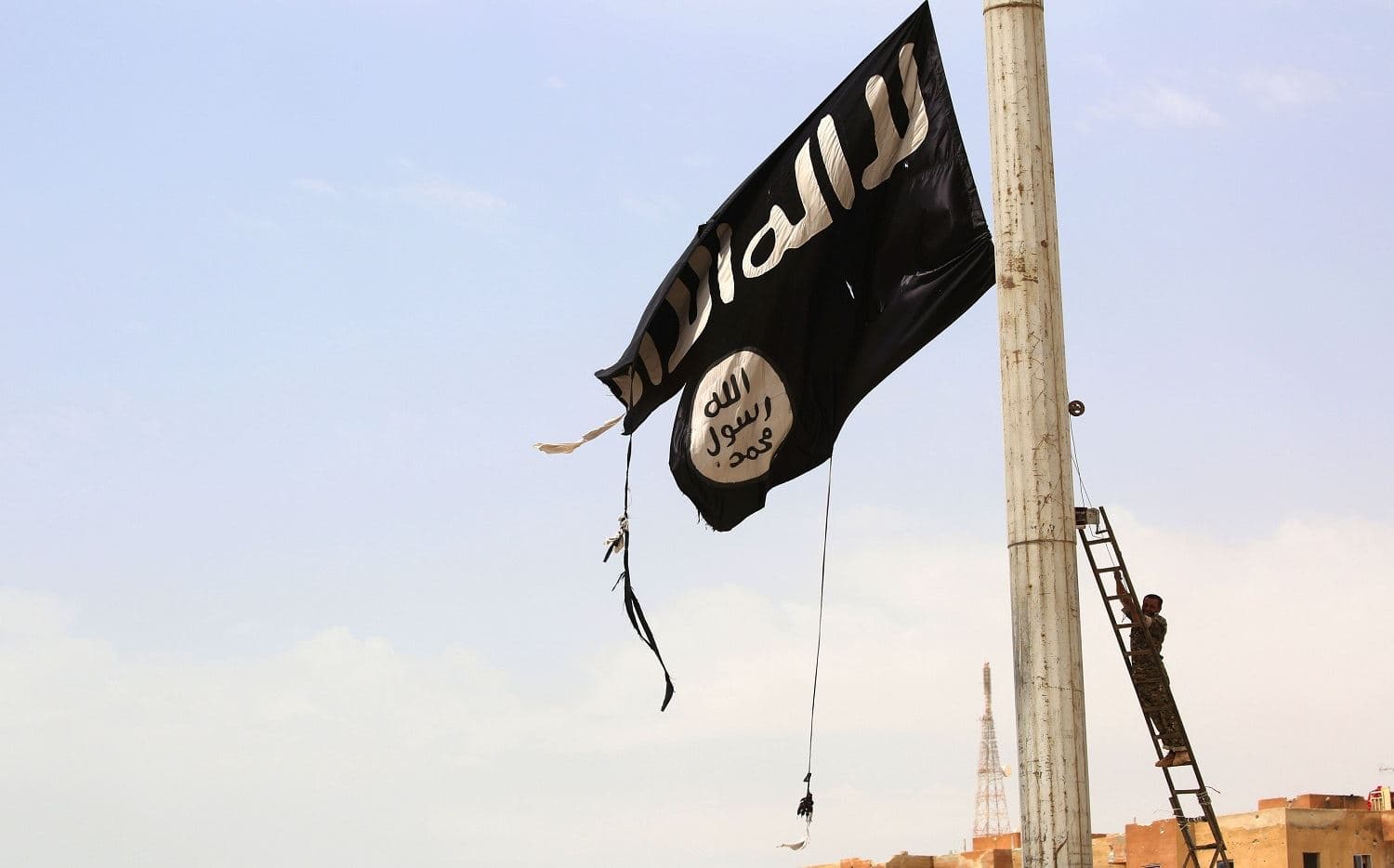 A member of the US-backed Syrian Democratic Forces removes an ISIS flag in the town of Tabqa in April 2017. Photo: Delil Souleiman/AFP