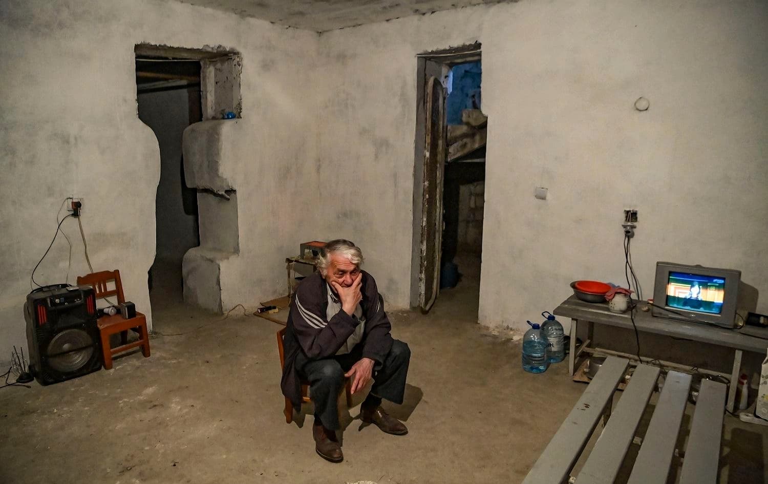 A man sits by a television set in a shelter arranged in a basement on October 9, 2020 in Martuni, Nagorno-Karabakh on October 10, 2020. Photo: Aris Messinis / AFP