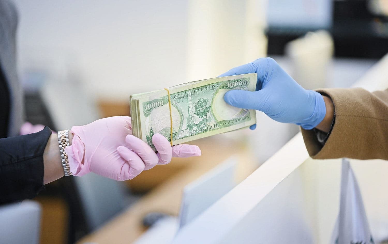 A bank employee hands Iraqi dinars to a customer. The government is attempting to co-opt the Central Bank of Iraq to its political agenda, warns Farhad Alaaldin, chairman of the Iraqi Advisory Council. File photo: Bilind T. Abdullah/Rudaw