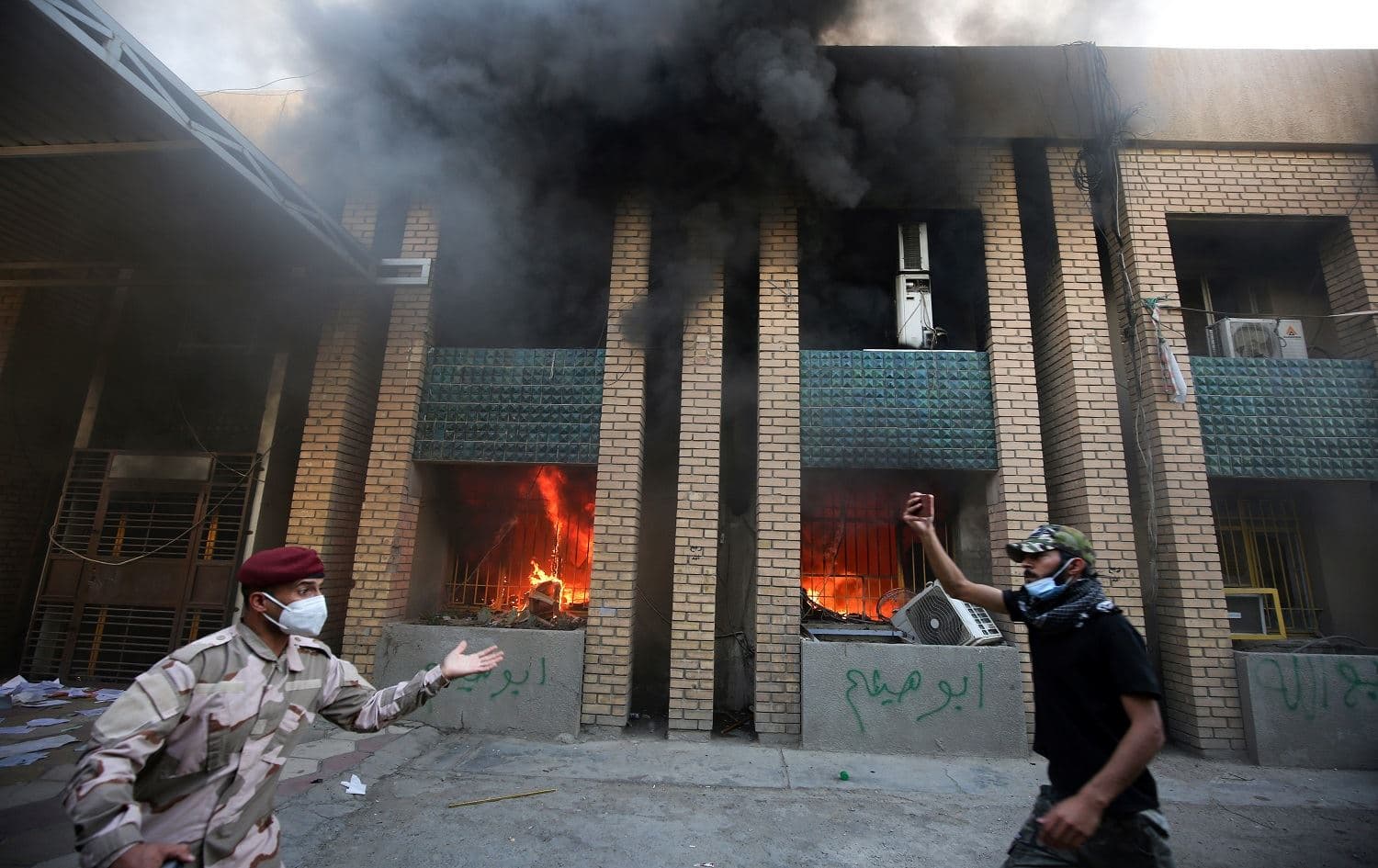 A member of the Iraqi security forces intervenes as demonstrators burn down the KDP office in Baghdad on October 17, 2020. Photo: Ahmad al-Rubaye/AFP