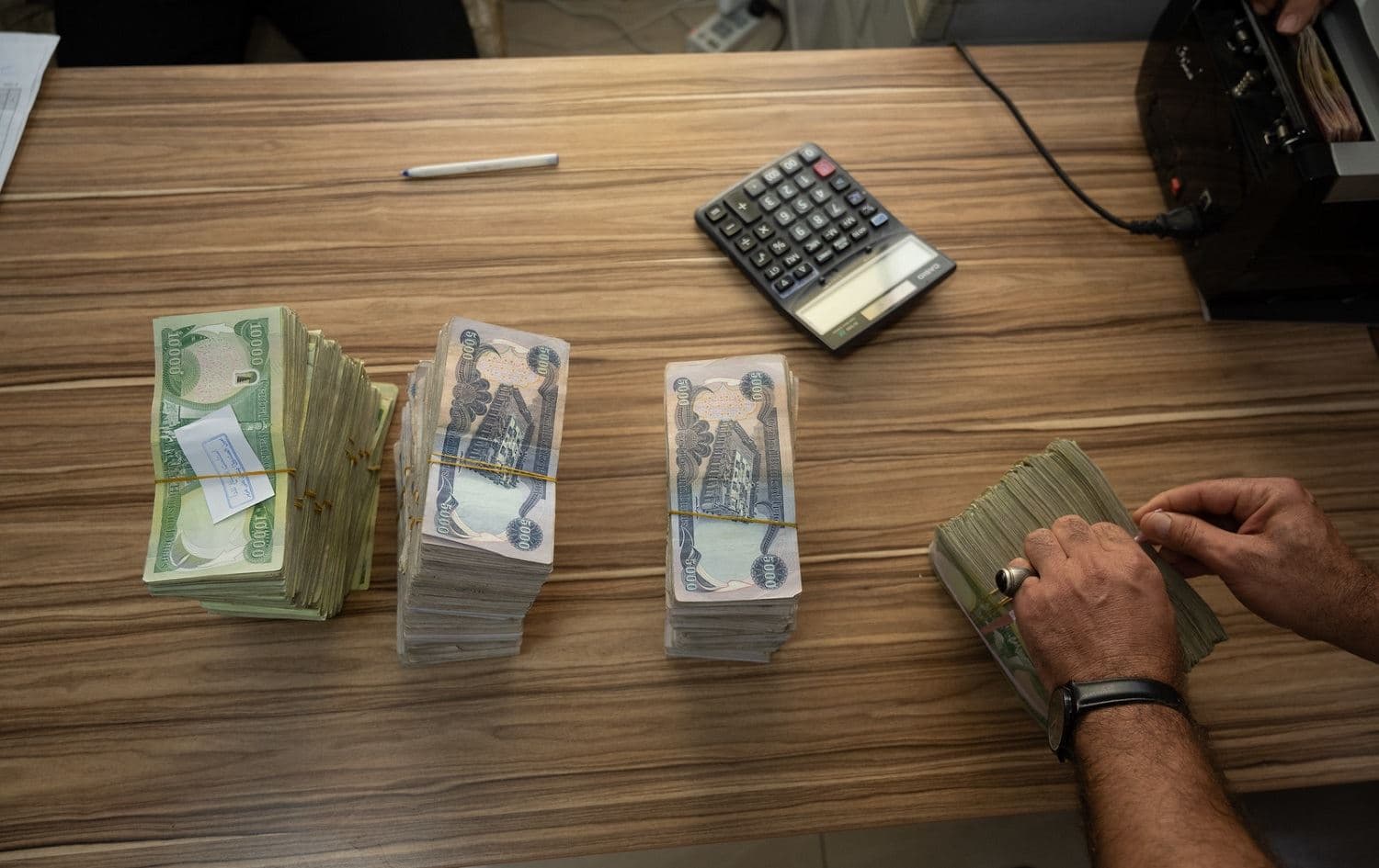 An employee of an Erbil bank counts piles of dinar notes. File photo: Bilind T. Abdullah/Rudaw