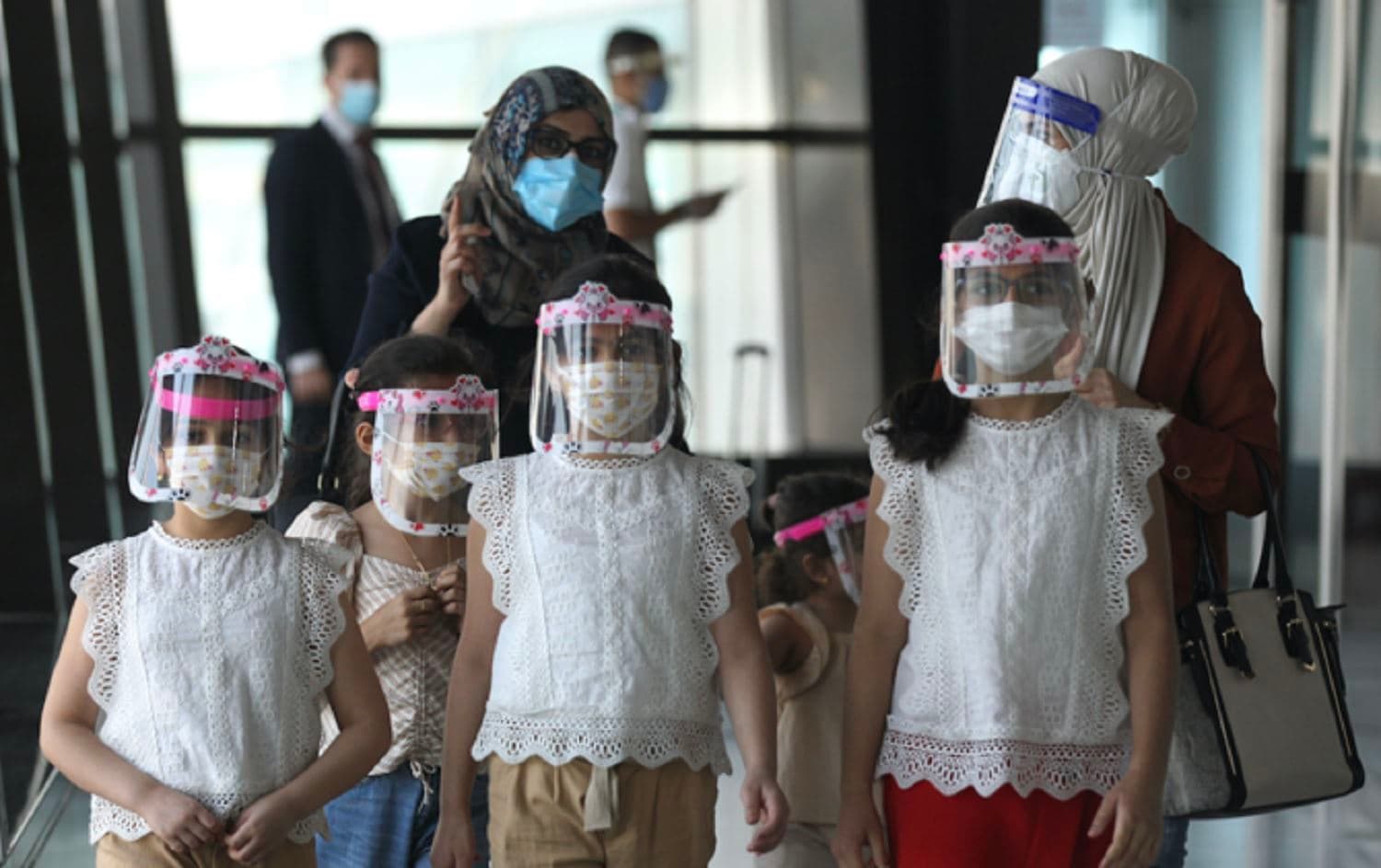 An Iraqi family wearing protective masks walk through the departure hall of Baghdad International Airport in July 2020. Photo: AFP
