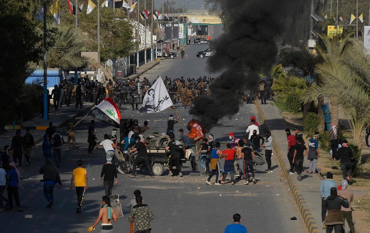 Iraqi security forces form a human barrier as they face anti-government demonstrators in Najaf on March 14, 2021. Photo: Ali Najafi/AFP