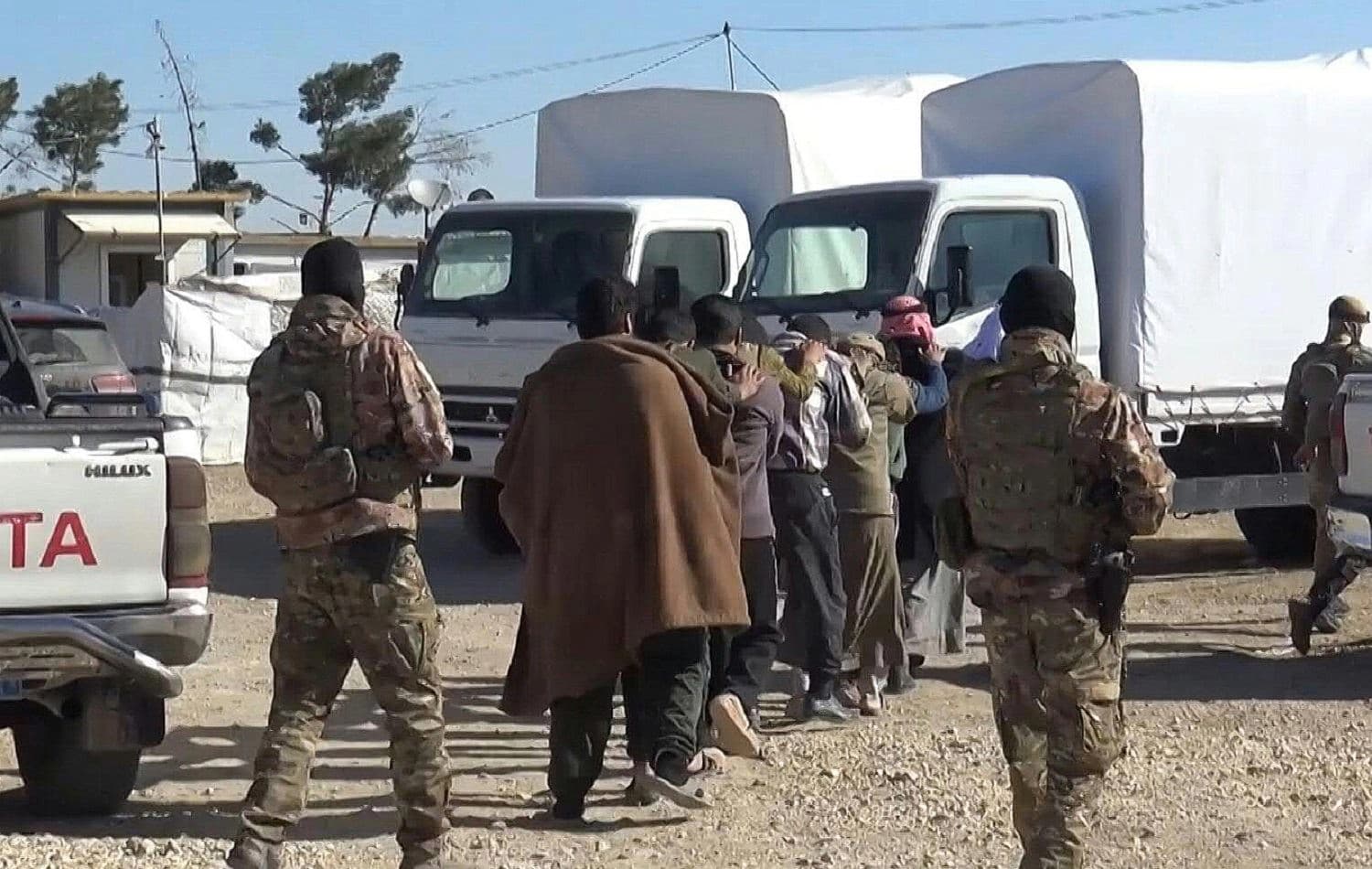 Kurdish-led forces march men towards vehicles at al-Hol camp. Photo: YPG Press Office / AFP