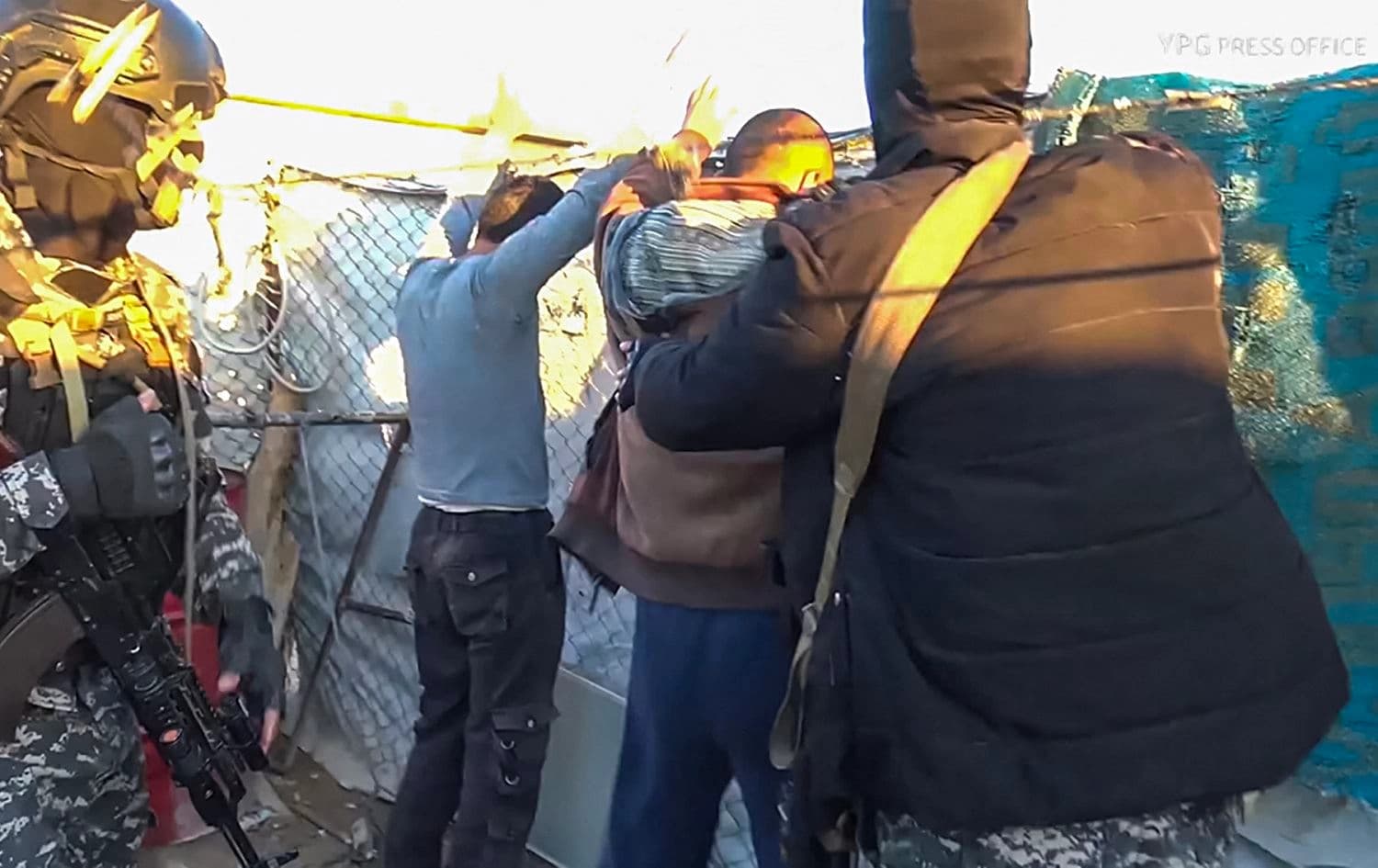 Kurdish People's Protection Units (YPG) forces line=up men by a fence during a security operation in al-Hol camp on March 28, 2021. Photo: YPG press office/AFP