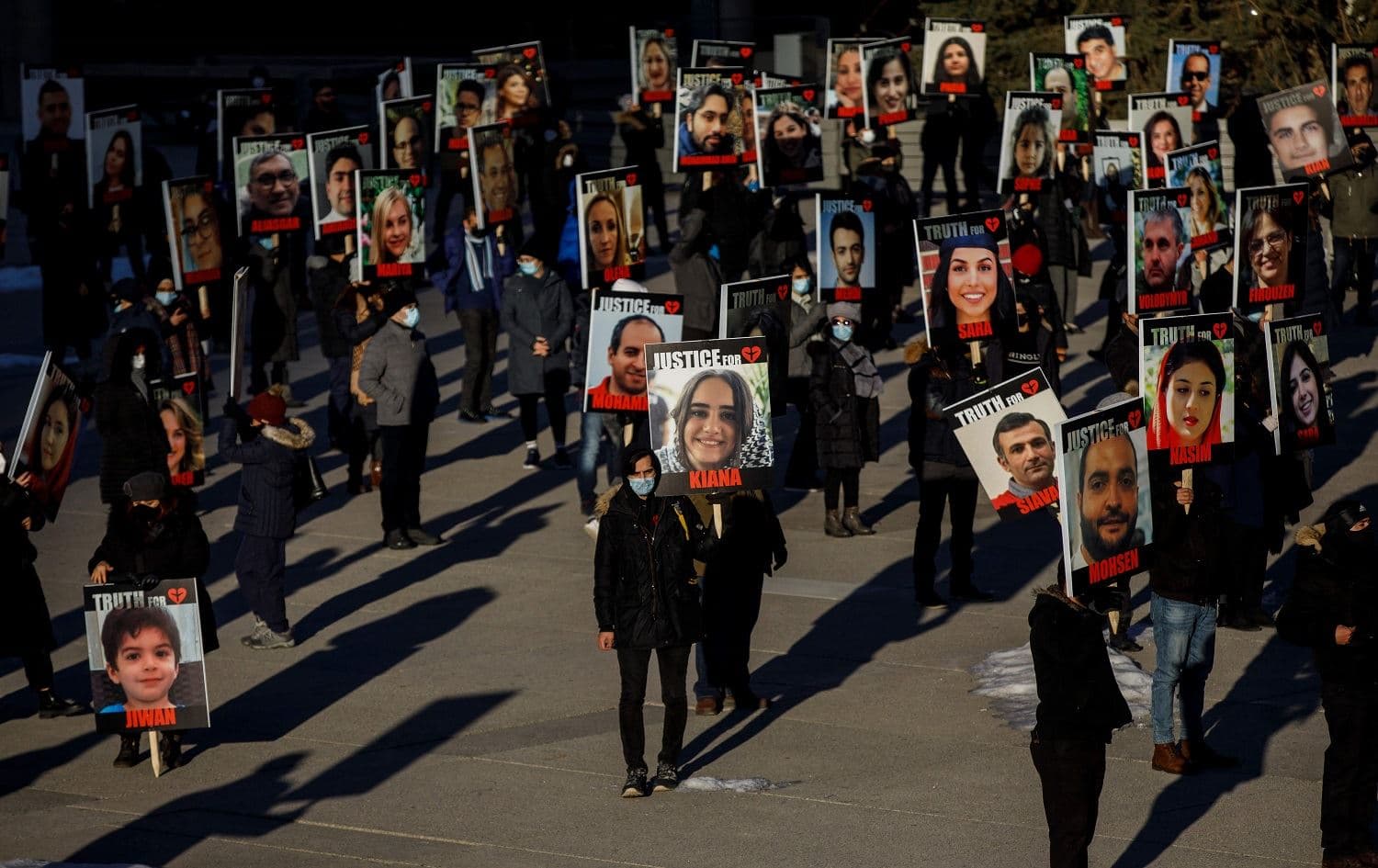 People hold signs with images of the victims of downed Flight 752 on January 8, 2021. Photo: AFP