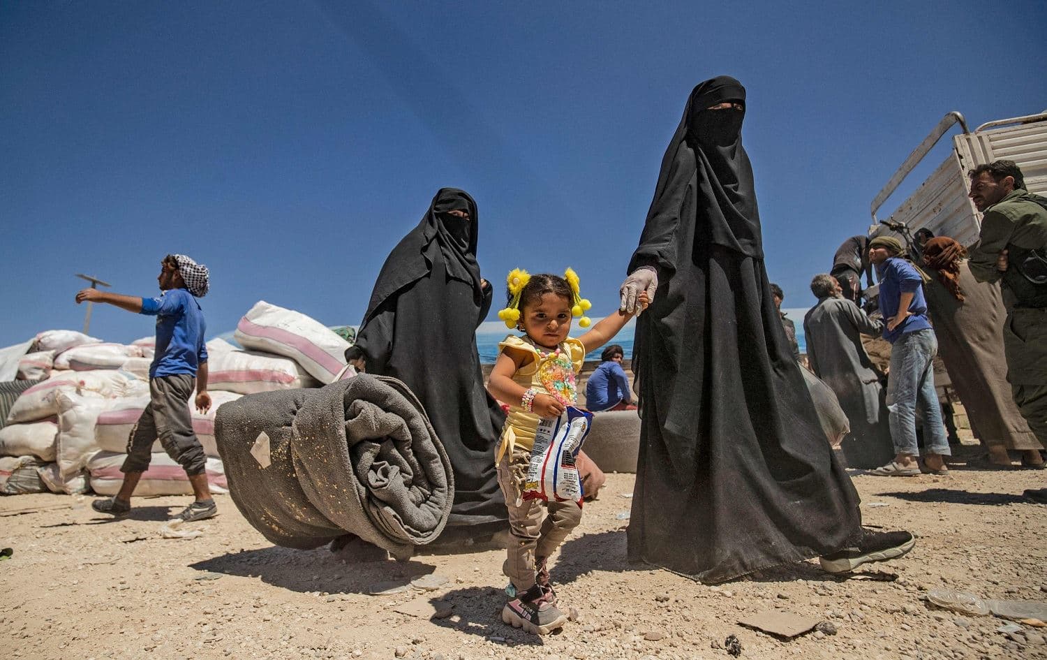 Women walk with children and belongings ahead of departure as another group of Syrian families is released from the Kurdish-run Al-Hol camp in northeast Syria on May 11, 2021. Photo: Delil Souleiman/AFP