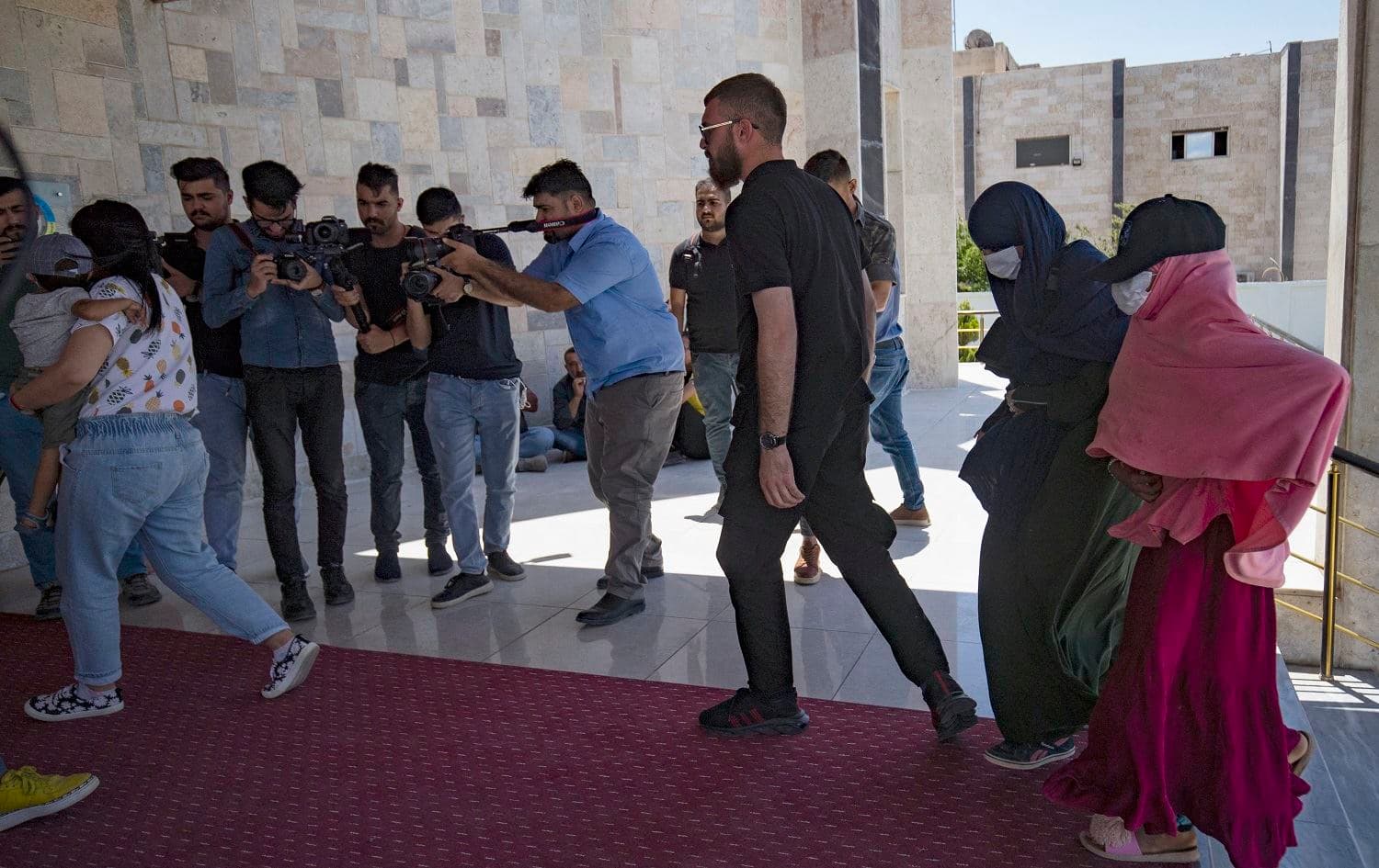 Members of Kurdish security forces accompany ISIS-linked Dutch nationals in Qamishlo on June 5, 2021. Photo: Delil Souleiman/AFP
