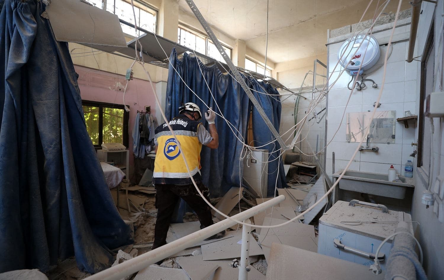 A member of Syria's Civil Defence service (White Helmets) inspects the damage in one of the rooms of the Al-Shifaa hospital, a day after it was hit by artillery shells in the rebel-held northern Syrian city of Afrin on June 13, 2021. Photo: AFP/Omar Haj Kadour