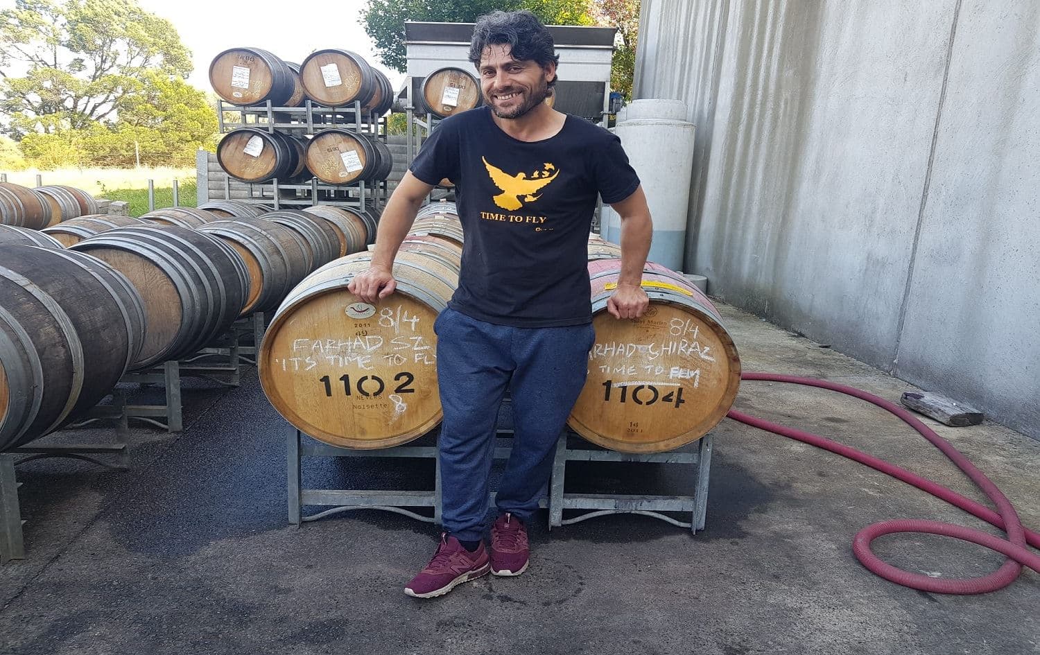 Farhad Bandesh stands next to barrels of wine at his business in Australia. Photo: Farhad Bandesh