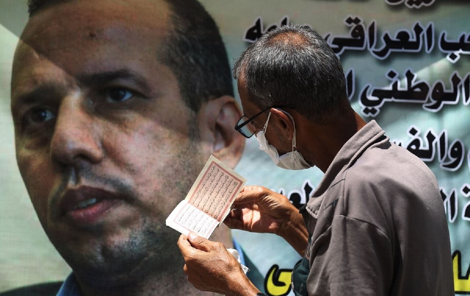 A person stands in front of a poster of murdered security analyst Husham al-Hashimi. File photo: Ahmad al-Rubaye/AFP