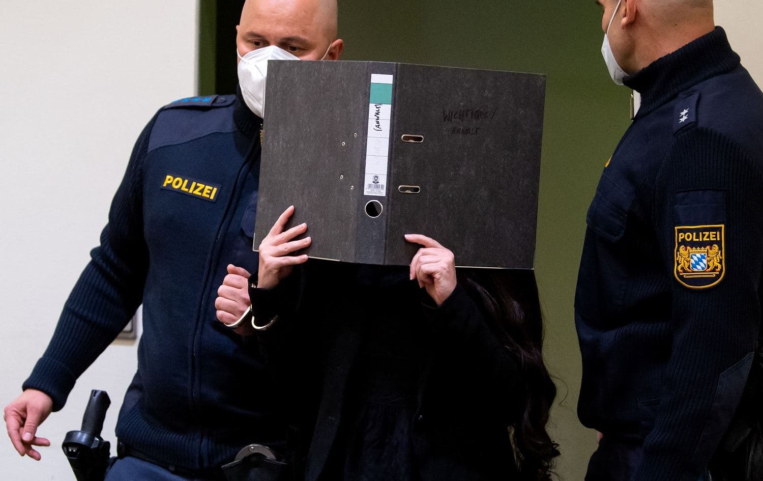 Jennifer W. (centre), a German woman who joined ISIS, hides her face behind a folder as she arrives at court for the verdict of her trial in Munich, Germany on October 25, 2021. Photo: Sven Hoppe/DPA/AFP