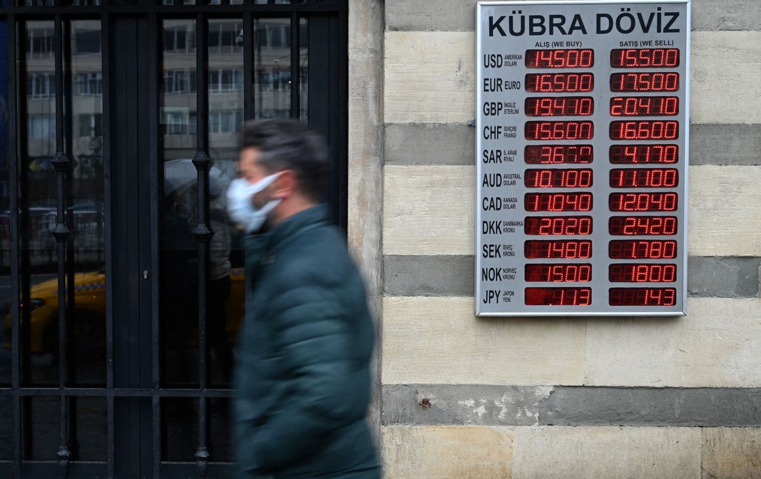 A man walks in front of a screen showing rates against Turkish lira near a currency exchange agency in Istanbul on December 16, 2021. Photo: AFP