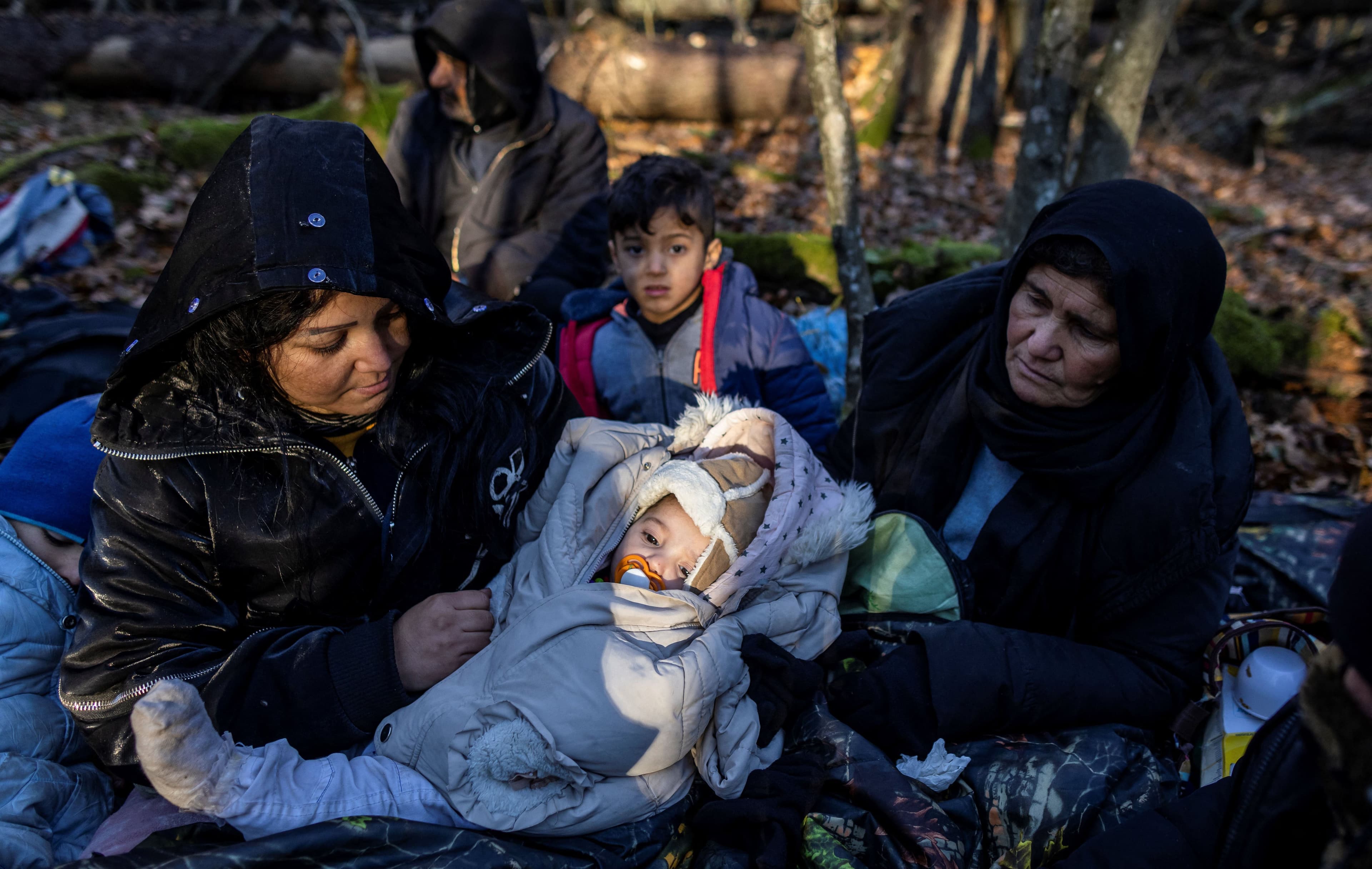 A Kurdish family from Dohuk in Iraq waits for the border guard patrol, near Narewka, Poland, on November 9, 2021. File Photo: Wojtek RADWANSKI/AFP