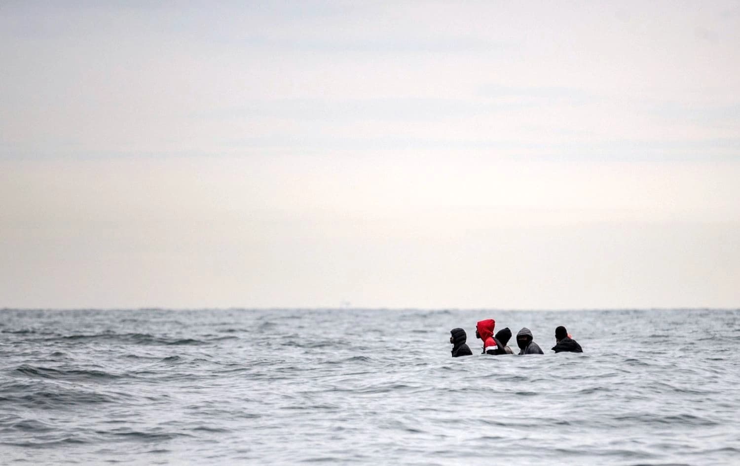 Five people crossing the English Channel, their vessel hidden. Photo: Sameer al-Doumy/AFP