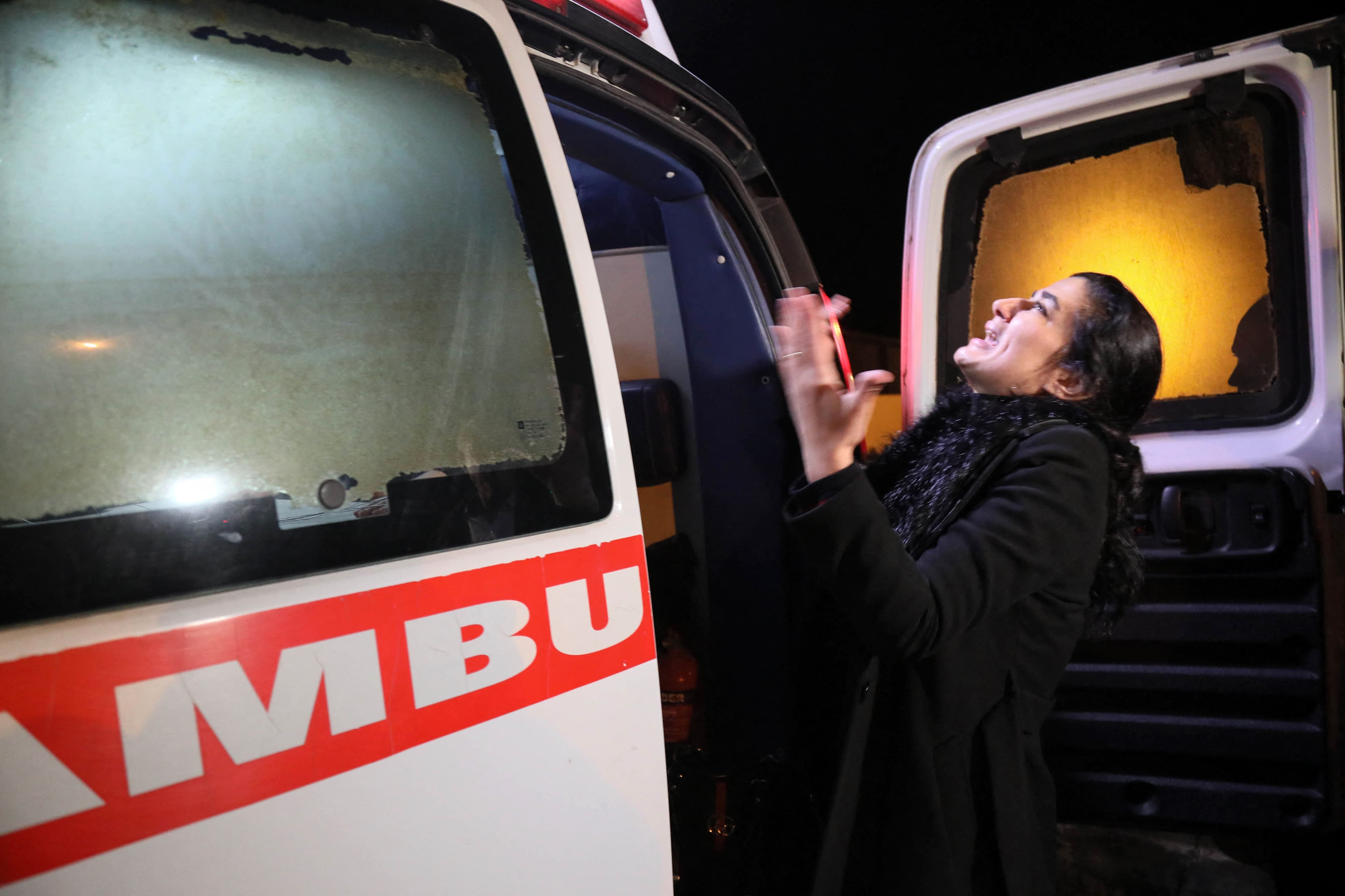 A woman mourns outside an ambulance carrying the remains of five Kurdish migrants who died as their boat capsized while attempting a crossing of the Aegean Sea, at Erbil airport on February 1, 2022. Photo: Safin Hamed/AFP