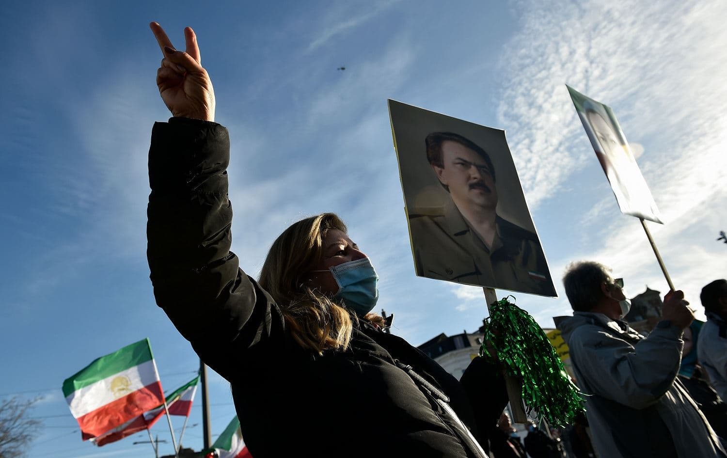 People wave the former Iranian flag and hold portraits as they protest outside the Antwerp courthouse, on February 4, 2021, during the trial of four suspects including an Iranian diplomat accused of taking part in a plot to bomb an opposition rally in France. Photo: John Thys/AFP