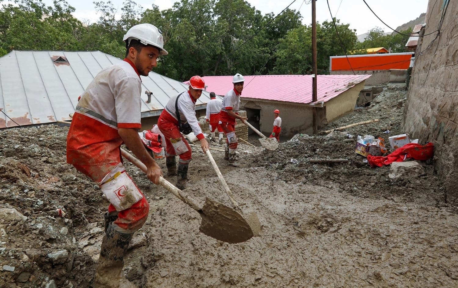 A handout picture provided by the Iranian Red Crescent (RCS) shows its personnel clearing mud deposited between houses following a flash flood in the Firouzkouh area east of Tehran, on July 30, 2022. Photo: AFP