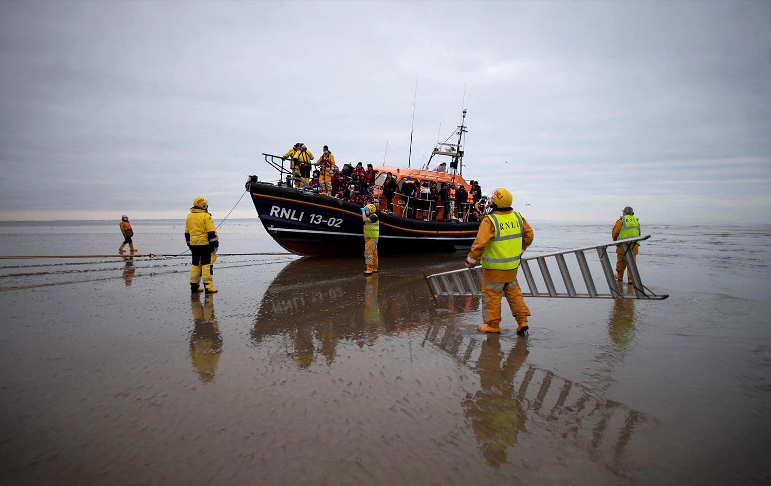In this file photo taken on December 16, 2021 members of the RNLI (Royal National Lifeboat Institution) prepare to help migrants ashore off an RNLI lifeboat at a beach in Dungeness on the southeast coast of England. Photo: Ben Stansall/AFP