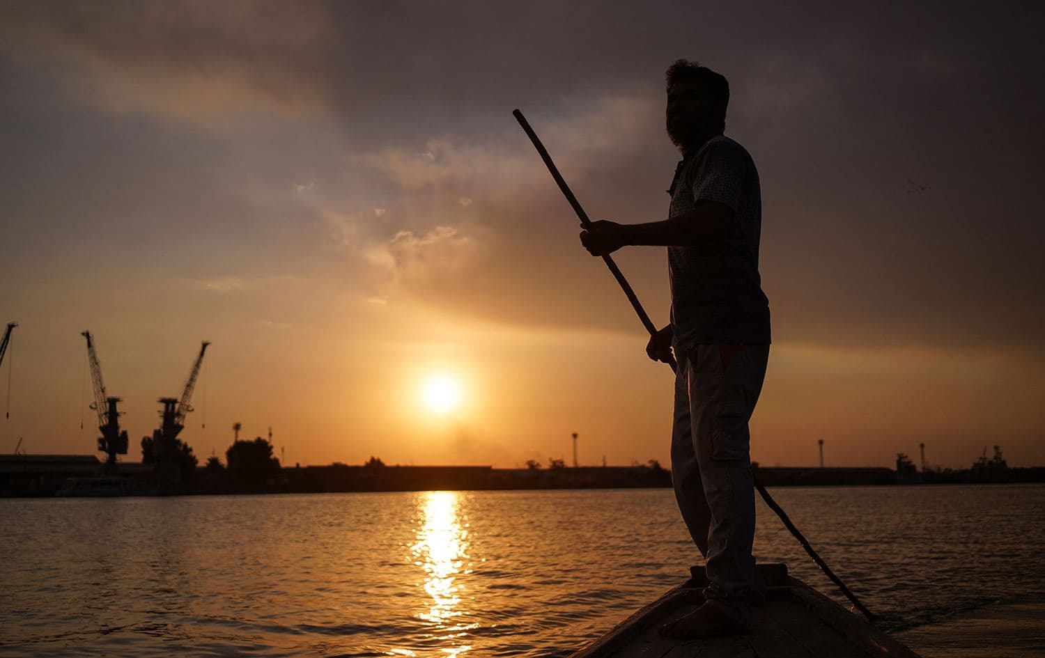 Iraqi fisherman Naim Haddad, 40, stands barefoot on his boat at sunset on Shatt al-Arab, the confluence of the Tigris and Euphrates rivers that empties into the Gulf, near the city of Basra in southern Iraq, on February 12, 2022. Photo: Aymen Henna/AFP