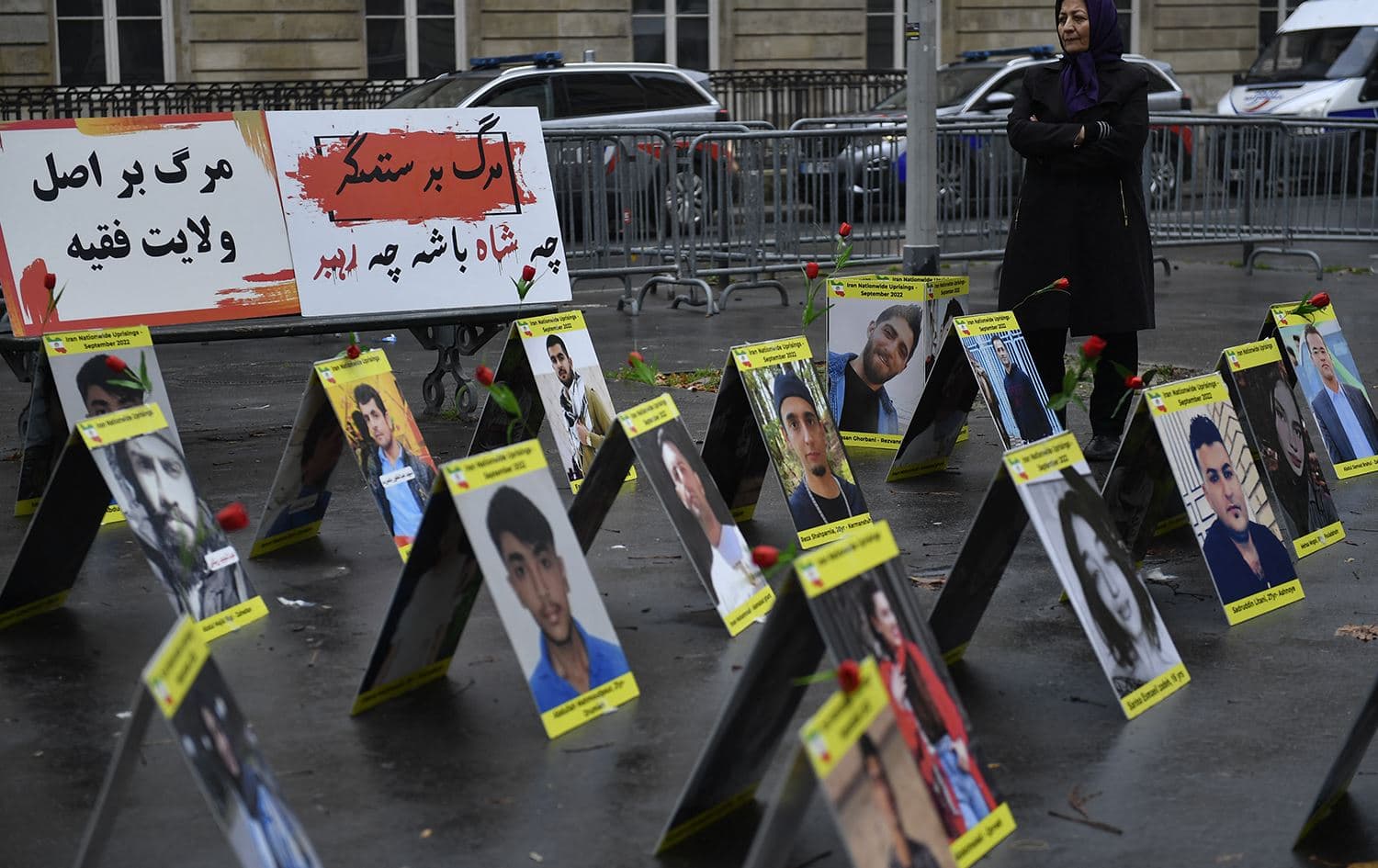 A protester stands next to placards with portraits of the victims of Iran's repression, near the French National Assembly in Paris on December 6, 2022. Photo: Julian De Rosa/AFP
