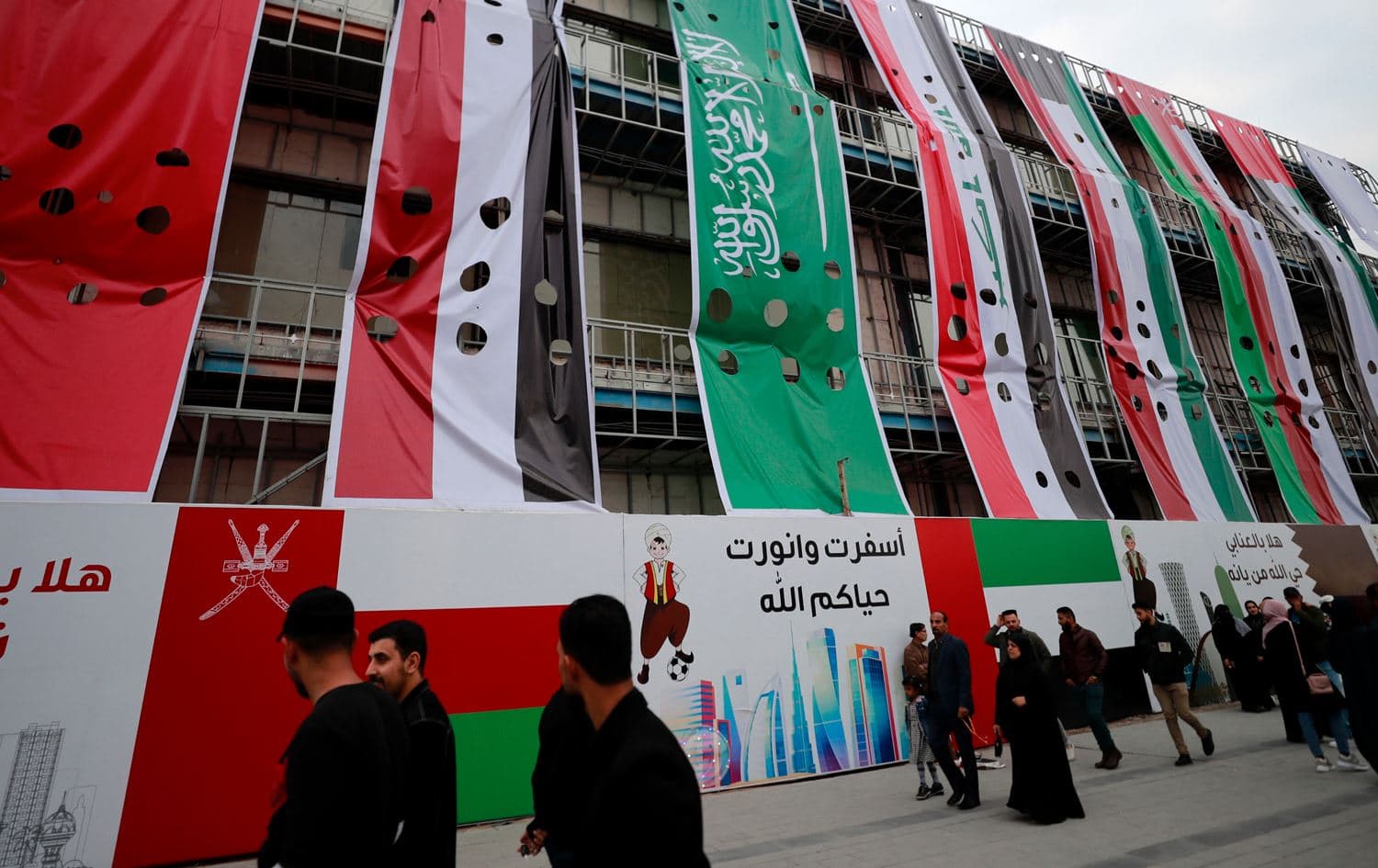 People walk in front of a building bearing flags of Arab nations on its facacde in Basra on January 5, 2023. Photo: Ahmad al-Rubaye/AFP