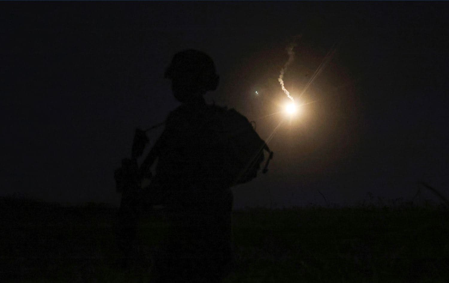 The silhouette of an Israeli soldier is outlined in the sky by a flare fired to search for a rocket that landed near Kibbutz Meitsar in the Israeli annexed Golan Heights, April 9, 2023. Photo: Jalaa Marey/AFP