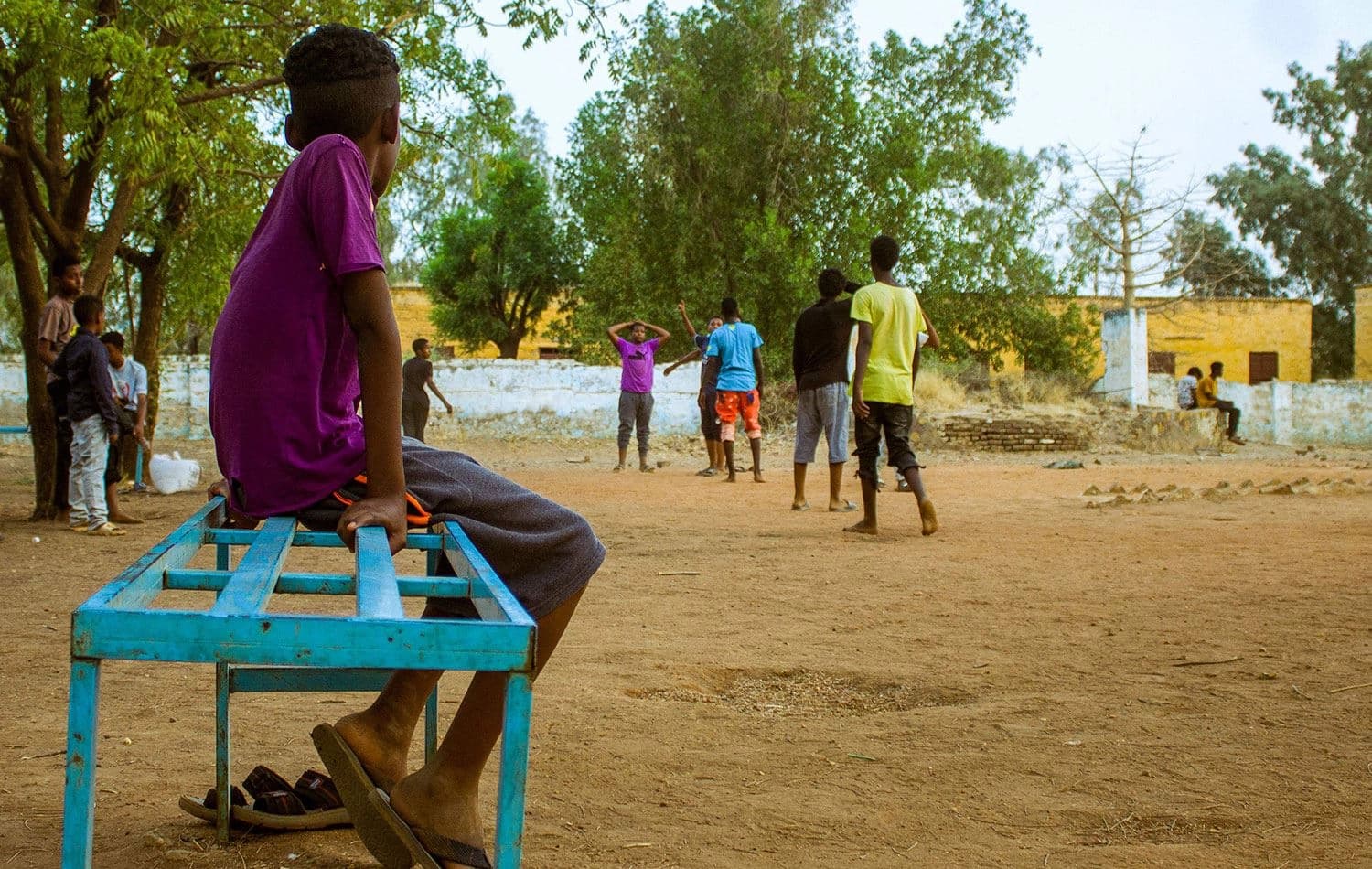 29 Mayıs 2023'te Sudan'ın El Cezire eyaletinin başkenti Wad Medeni'deki çatışmalar nedeniyle yerinden edilenler için kurulan Madrasa al-Gharbiya kampındaki toprak sahada oynayanları izleyen bir çocuk. / AFP