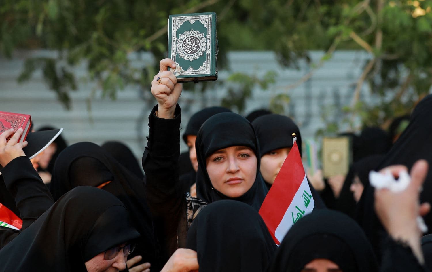 A woman holding up a copy of the Quran near Baghdad's Green Zone, on July 22, 2023 in protest of the burning of the Islamic holy book in Sweden and Denmark. Photo: Murtaja Lateef/AFP