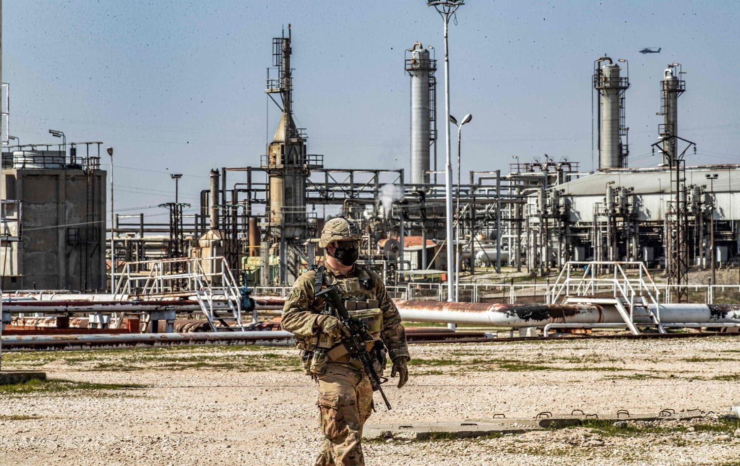 A United States soldier looks on while an AH-64 Apache assault helicopter flies above during a patrol by the Suwayda oil fields in Hasaka province, northeastern Syria on February 13, 2021. Photo: AFP.