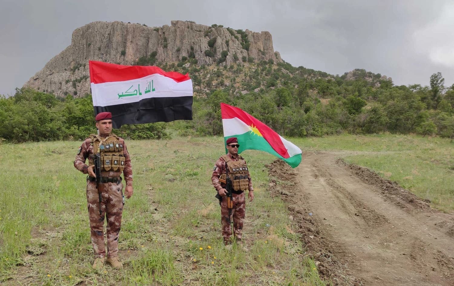 دوو ئەندامی هێزەکانی پاسەوانی سنوور کە ئاڵای کوردستان و عێراقیان بەرزکردووەتەوە