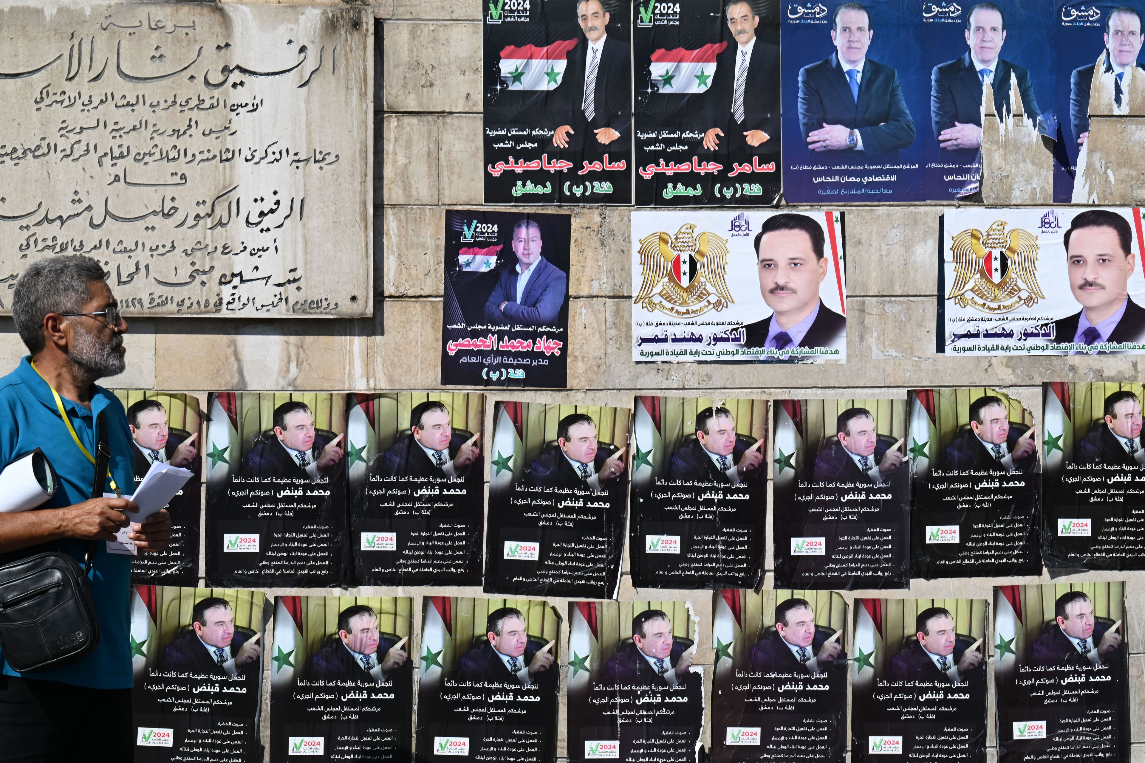 A Syrian man walks past election campaign posters after voting in the country's legislative election at a polling station in Damascus on July 15, 2024. Photo: AFP