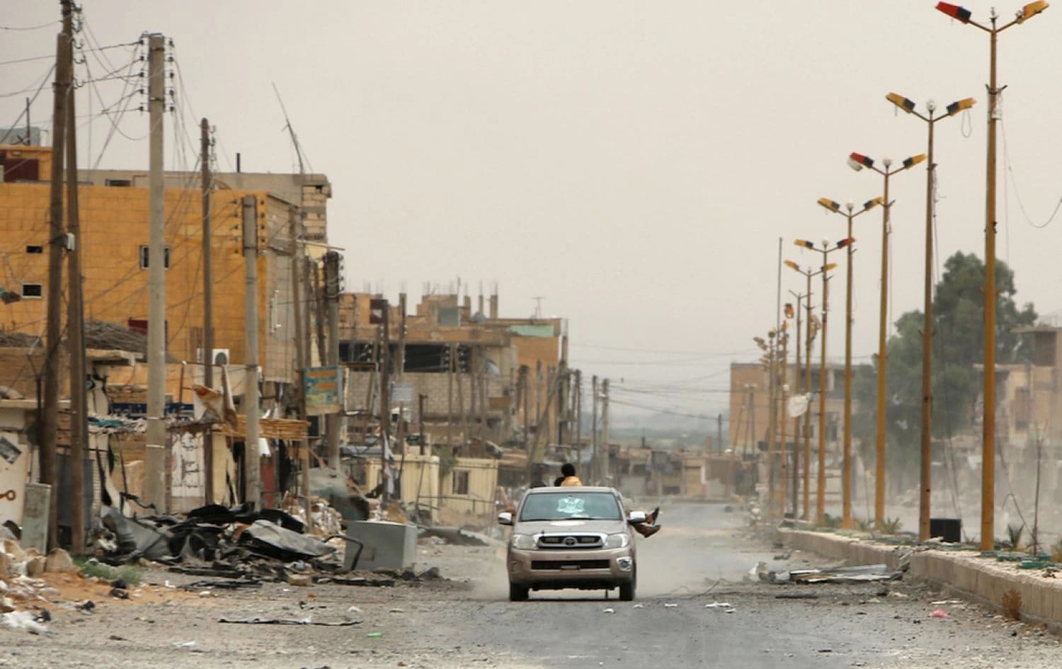 A car drives through a damaged street on the outskirts of Deir ez-Zor on September 24, 2017. Photo: AFP