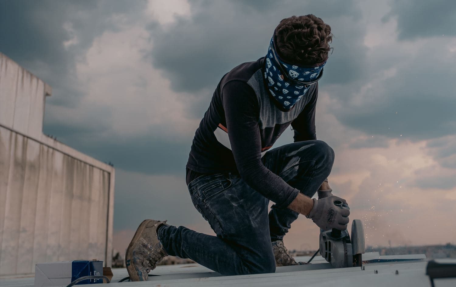 Young worker using a grinder on a roof. Photo: Rudaw/Blind T. Abdullah
