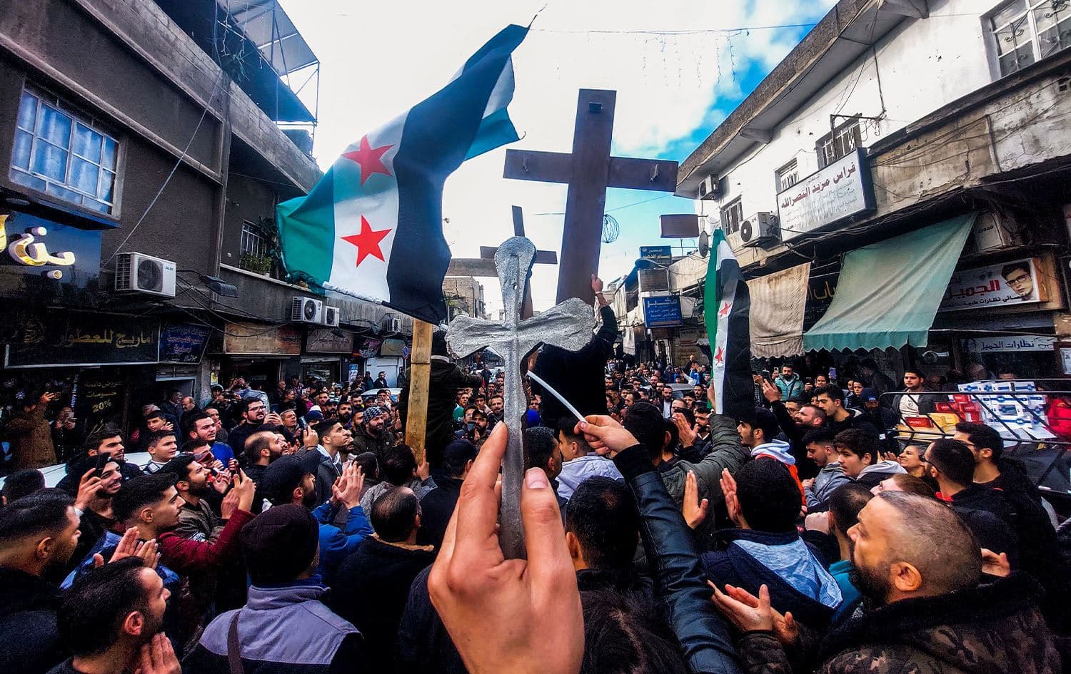 Christian Syrians lift crosses and independence-era flags as they rally in the Duweilaah area of Damascus on December 24, 2024, to protest the burning of a Christmas tree near Hama in central Syria. Photo: Louai Beshara/AFP