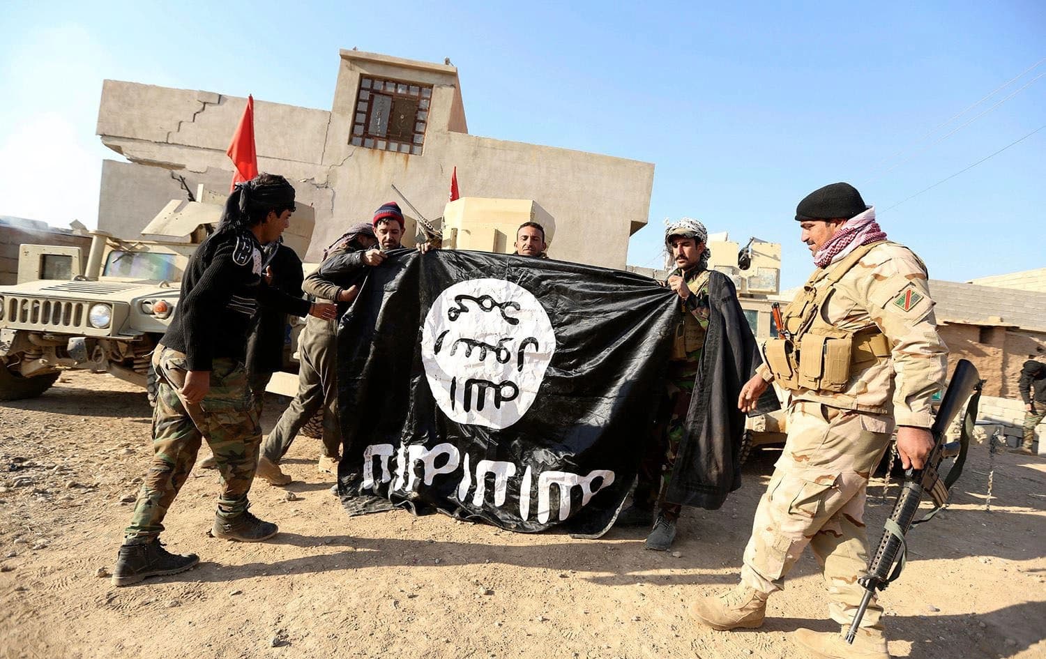 Iraqi army soldiers celebrate as they hold an ISIS flag they captured during a military operation to regain control of a village outside Mosul on November 29, 2016. Photo: Hadi Mizban/AP
