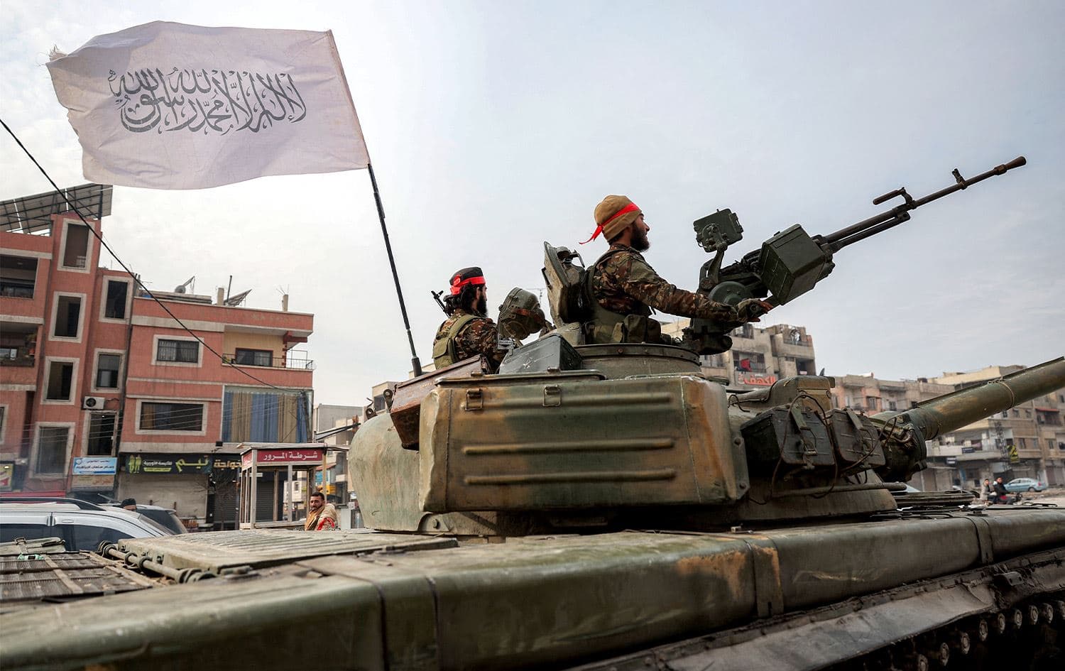 An Islamic black-and-white flag bearing the Shahada (the creed stating a belief in one god and the acceptance that Mohammed was God's prophet) flies from a tank used by fighters loyal to the interim Syrian government while deployed in the Zahra district of Syria's west-central city of Homs on January 4, 2025. Photo: AFP