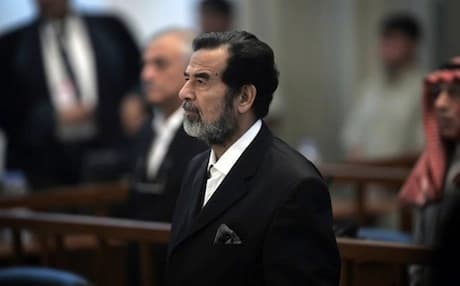 Saddam Hussein stands as an unseen witness is sworn in for testimony during his trial in Baghdad’s heavily fortified Green Zone, in Iraq, on October 19, 2006. Photo: AP