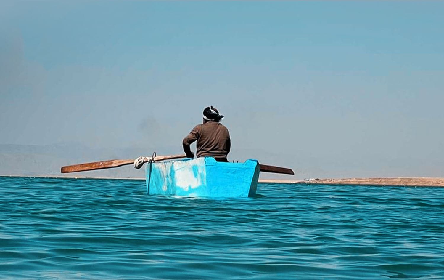 کەسێک لەسەر بەلەمێکەوە راوی ماسی دەکات