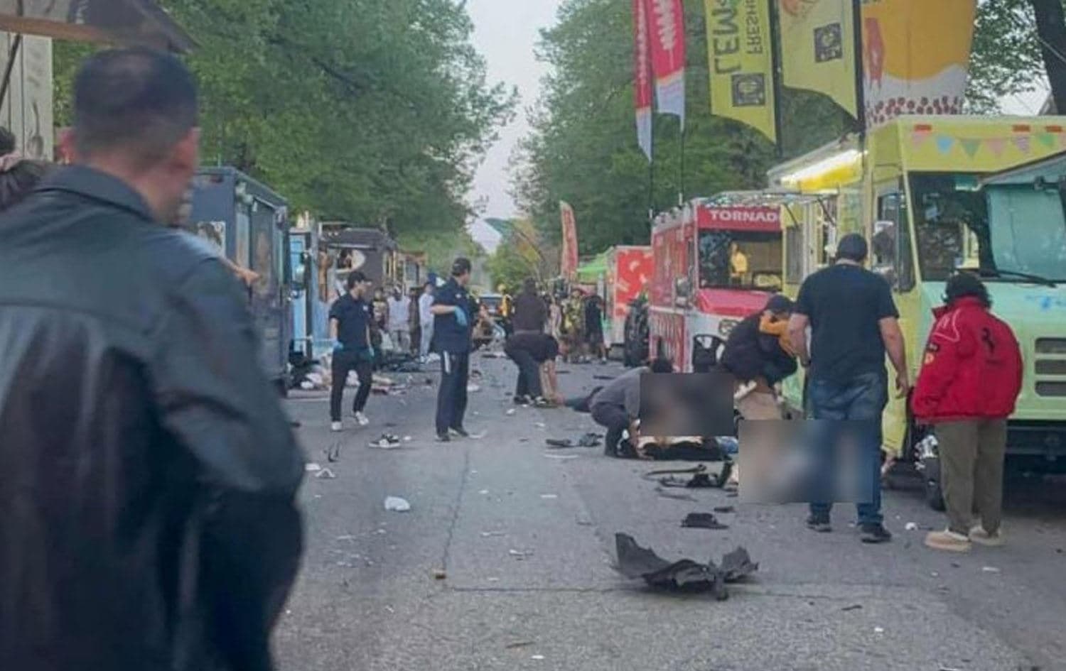 چەند کەسێک لەسەر شەقامێک لە شوێنی رووداوەکە کەوتوون