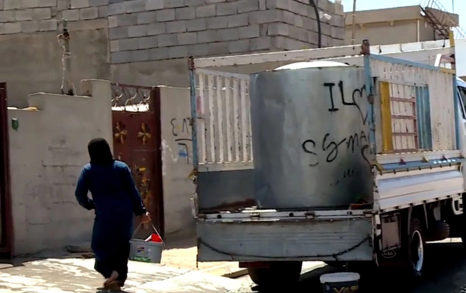 لە کۆڵانێکی ناحیەی شۆڕش لە قەزای چەمچەماڵ ژنێک بە دەبە ئاو دەباتەوە ماڵەوە. وێنە: رووداو