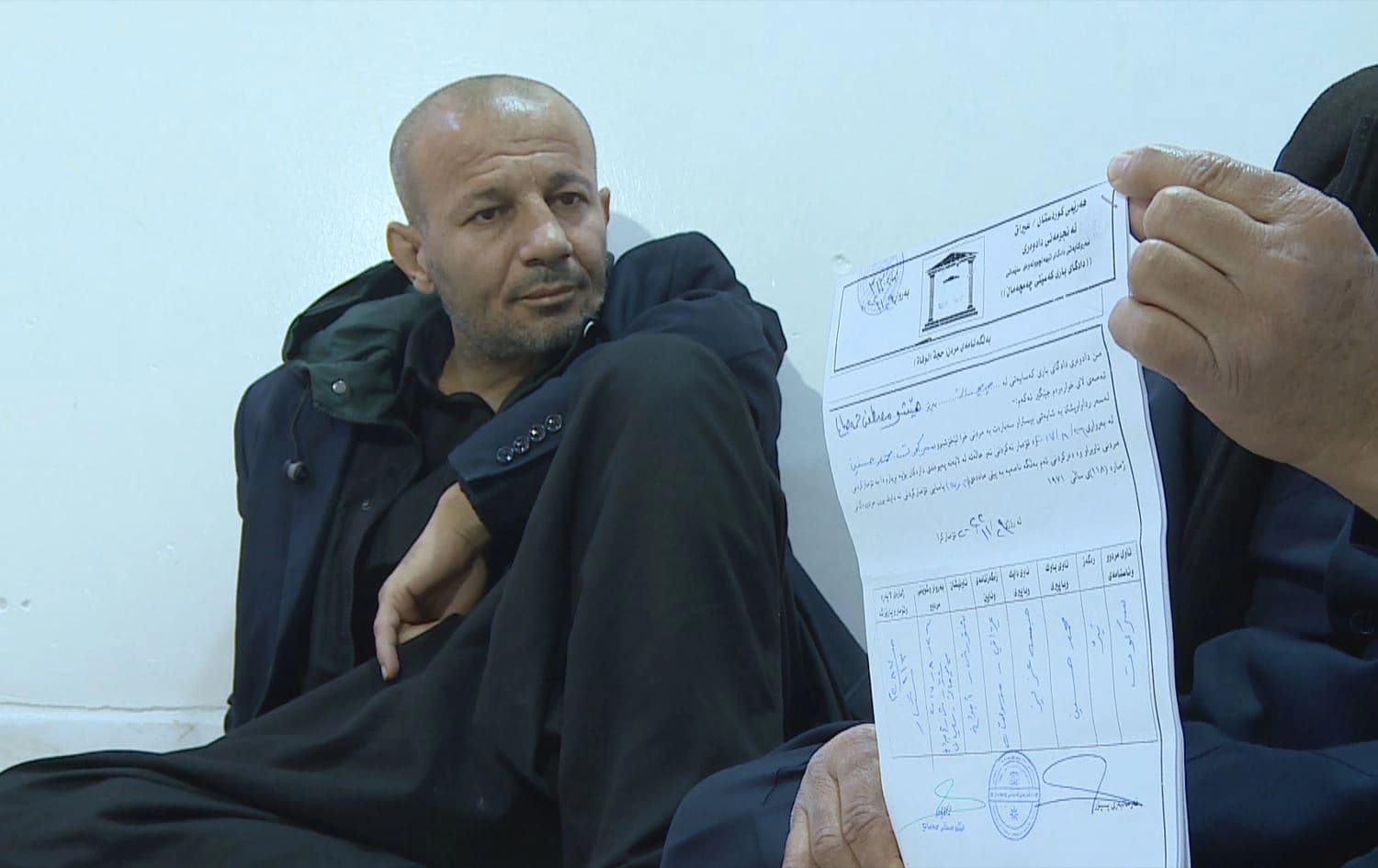 Sarkawt Mohammed, looking at his own death certificate, in Chamchamal district’s Shorsh subdistrict, Sulaimani province, on December 28, 2025. Photo: screengrab/Rudaw