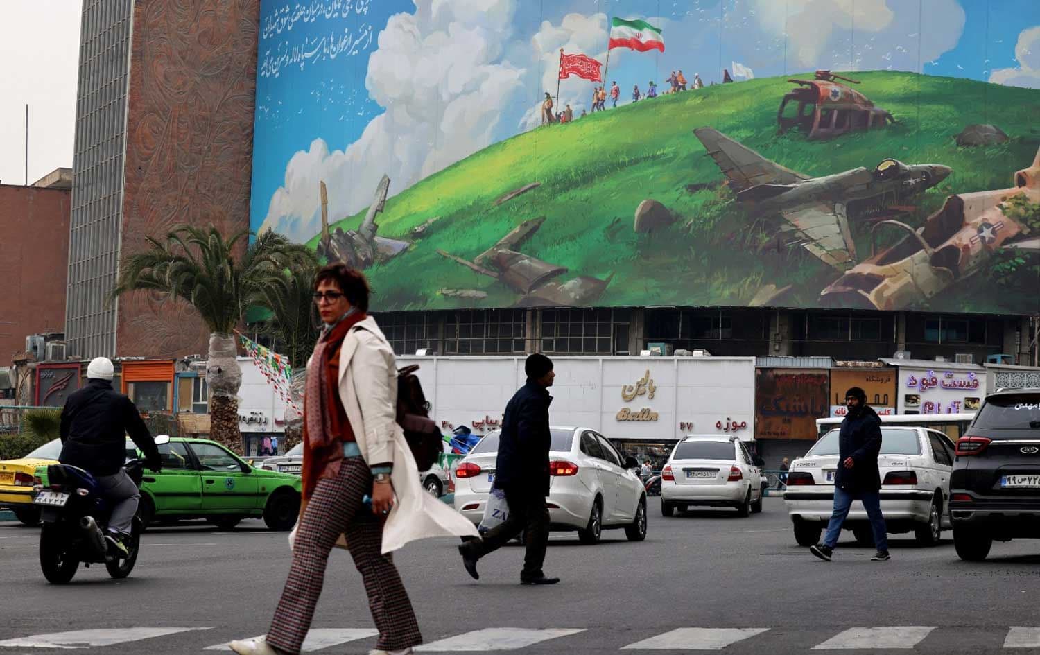 An Iranian woman walks past a huge anti-US billboard displayed on a building in Tehran's Valiasr Square on February 8, 2026. Photo: AFP