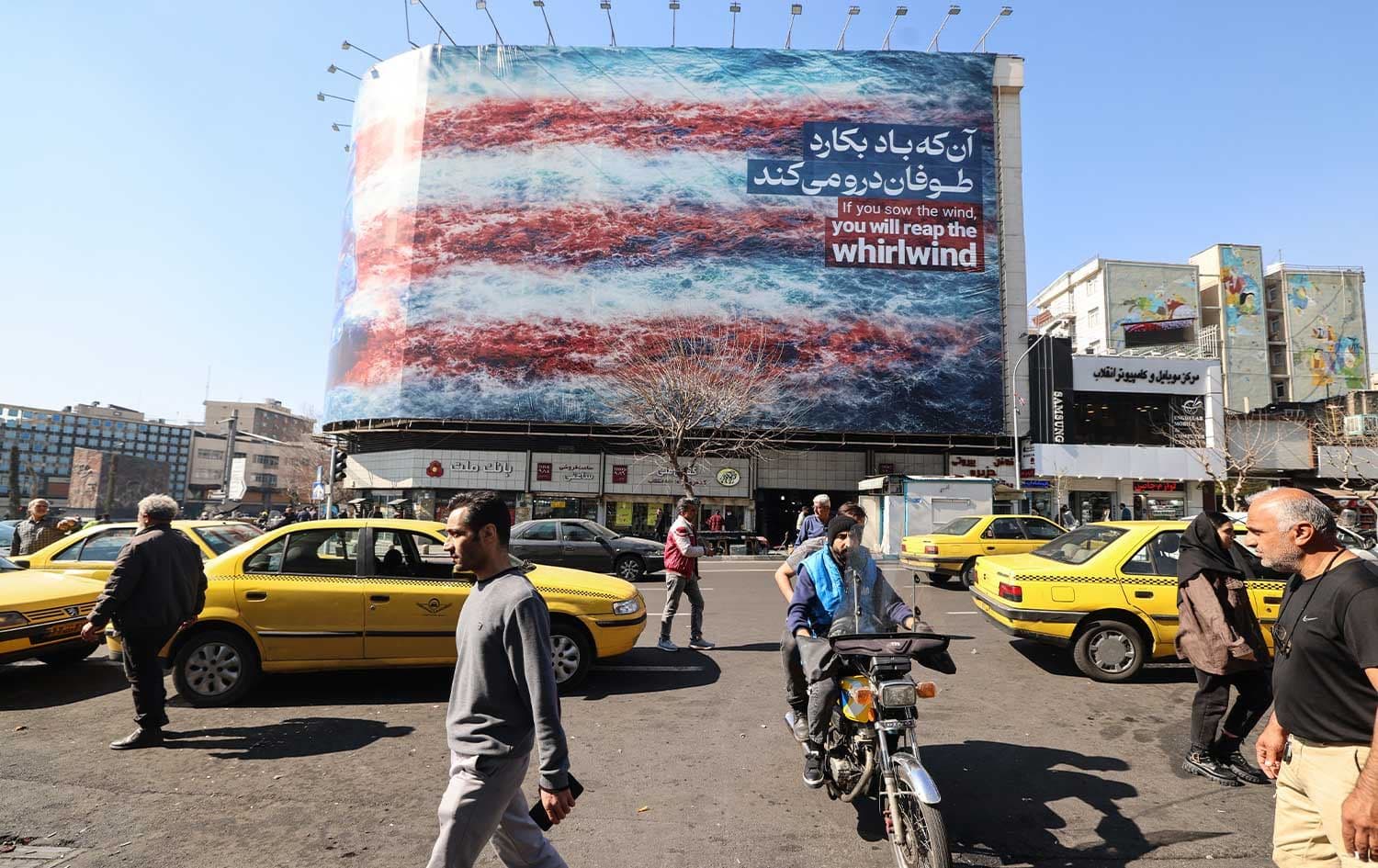 Iranians walk past an anti-US billboard installed on a building on Enqelab Square in Tehran on February 17, 2026. Photo: AFP