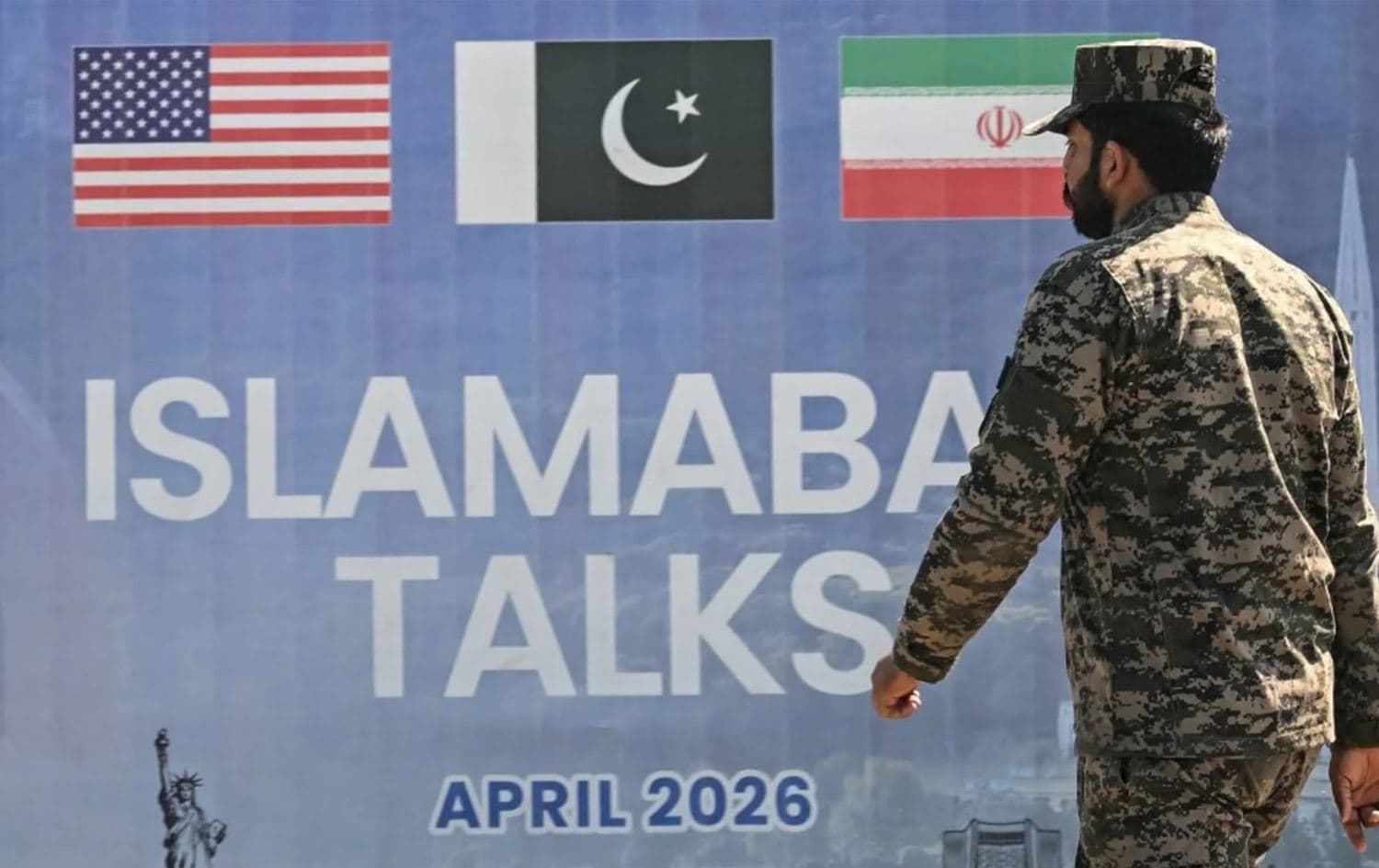 A Pakistani officer walks past a billboard for the US-Iran talks in Islamabad on April 12, 2026. Photo: AFP