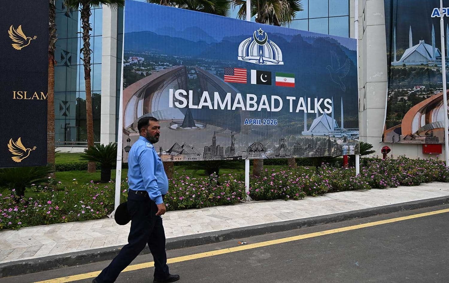 A police officer walks past a billboard for the US–Iran peace talks in Islamabad on April 11, 2026. Photo: AFP