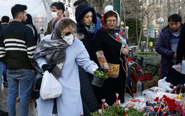 An Iranian woman wearing a protective face mask chooses traditional items ahead of Nowruz. Photo: AFP / STR