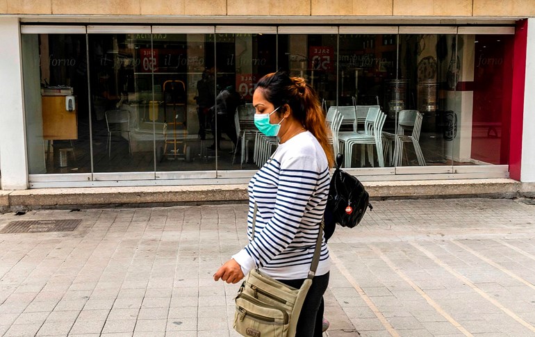 A woman walks past a closed restaurant in the old city of the Cypriot capital Nicosia, March 16, 2020. Photo: Iakovos Hatzistavrou / AFP