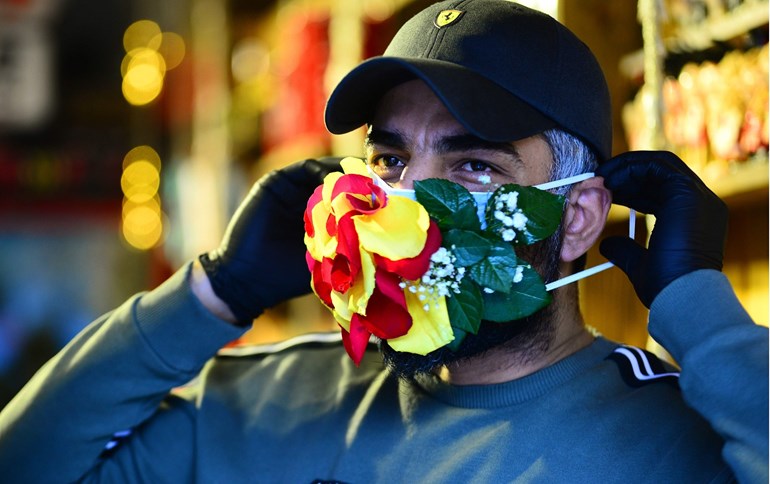 A florist wears an embellished mask that he sells at his shop in the central Iraqi holy city of Najaf on March 21, 2020. Photo: Haidar Hamdani / AFP 