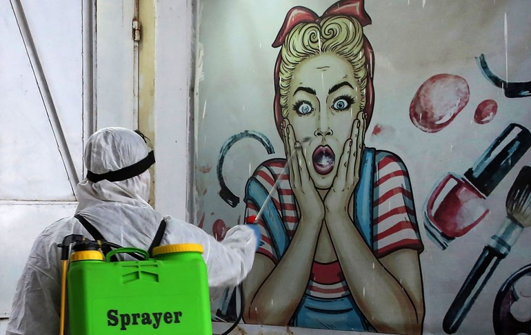 A volunteer disinfects a shop in Baghdad on March 21, 2020. Photo: Ahmad Al-Rubaye/ AFP